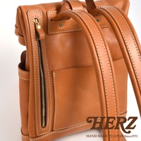 棕色皮革雙口袋折蓋後背包，有明顯的縫線和金色拉鍊，材質為皮革。