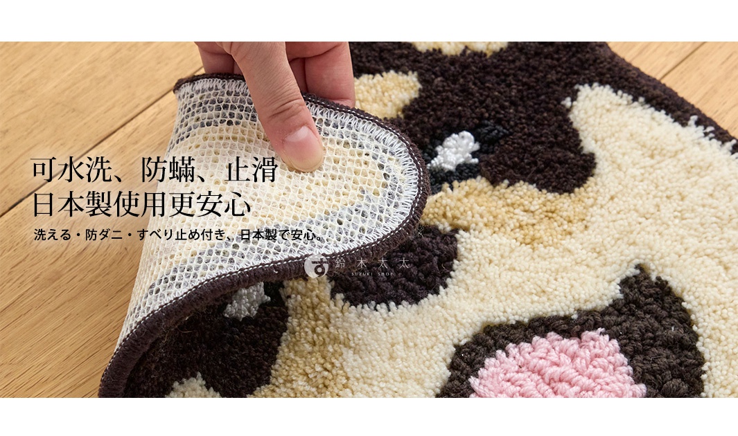 一隻手將狗狗造型椅墊的一角翻起，展示其網狀防滑背層結構。墊子表面由米色、棕色及粉色絨毛編織而成，整體呈現可愛的狗狗圖案。圖片左側疊加了文字，說明該產品具有可水洗、防蟎、防滑以及日本製造的特性，適合放置於室內地板使用。