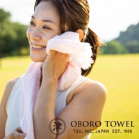 一位女性在戶外用粉紅色三層紗純棉掛脖毛巾擦拭臉部。