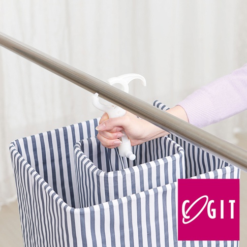 手持白色塑膠卡扣式通風晾曬架，掛在金屬桿上，下方是藍白條紋的布質收納袋。