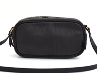 黑色皮革製成的職人手作隨身單肩小包，包身方形帶有圓潤邊緣，頂部有金色拉鍊，兩側有黑色皮革背帶。