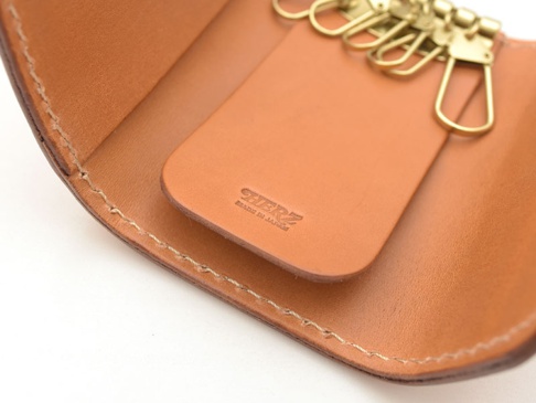 職人手作皮革經典鑰匙包，淺棕色皮革，內有六個金色掛鉤，皮革表面壓印品牌標誌。