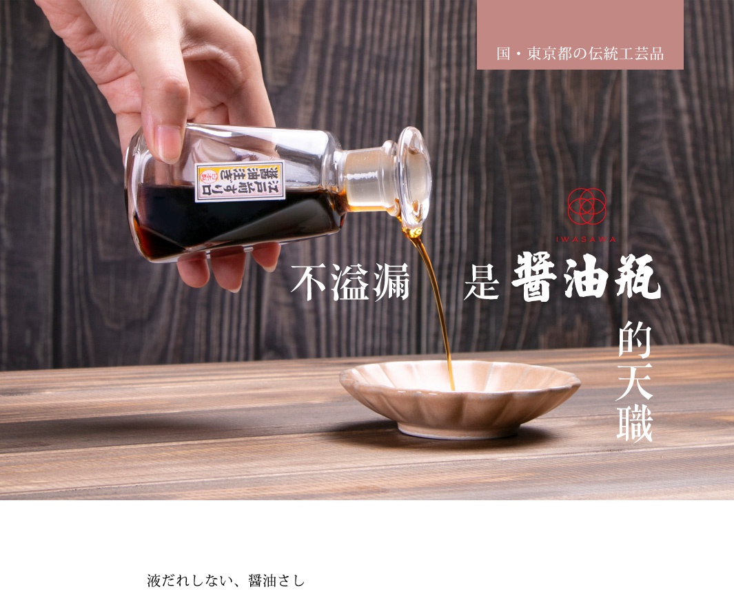 一只手持透明玻璃醬油瓶，瓶內裝有深褐色醬油，瓶口傾斜，醬油正緩慢滴入一個淺褐色陶瓷小碟中。瓶身上貼有日文標籤。背景為木紋桌面和木紋牆壁。