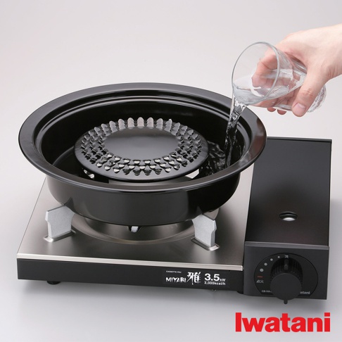 卡式爐專用網狀烤盤，黑色金屬材質，帶有銀色支架。網狀烤盤中央有水，一隻手正在往烤盤中倒水。