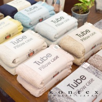 MOKU TUBE高彈性透氣枕套，展示多種顏色，包括淺粉、米白、淺藍、黃色、深藍及麻灰色。枕套採毛巾布材質，質地蓬鬆柔軟，包裝上印有「Tube Pillow case」字樣及尺寸資訊。