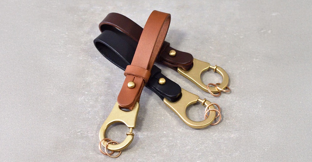 三款職人手作皮革鑰匙圈，包含棕色、黑色與咖啡色，皆採用真皮材質搭配黃銅色D型扣環與鑰匙圈。