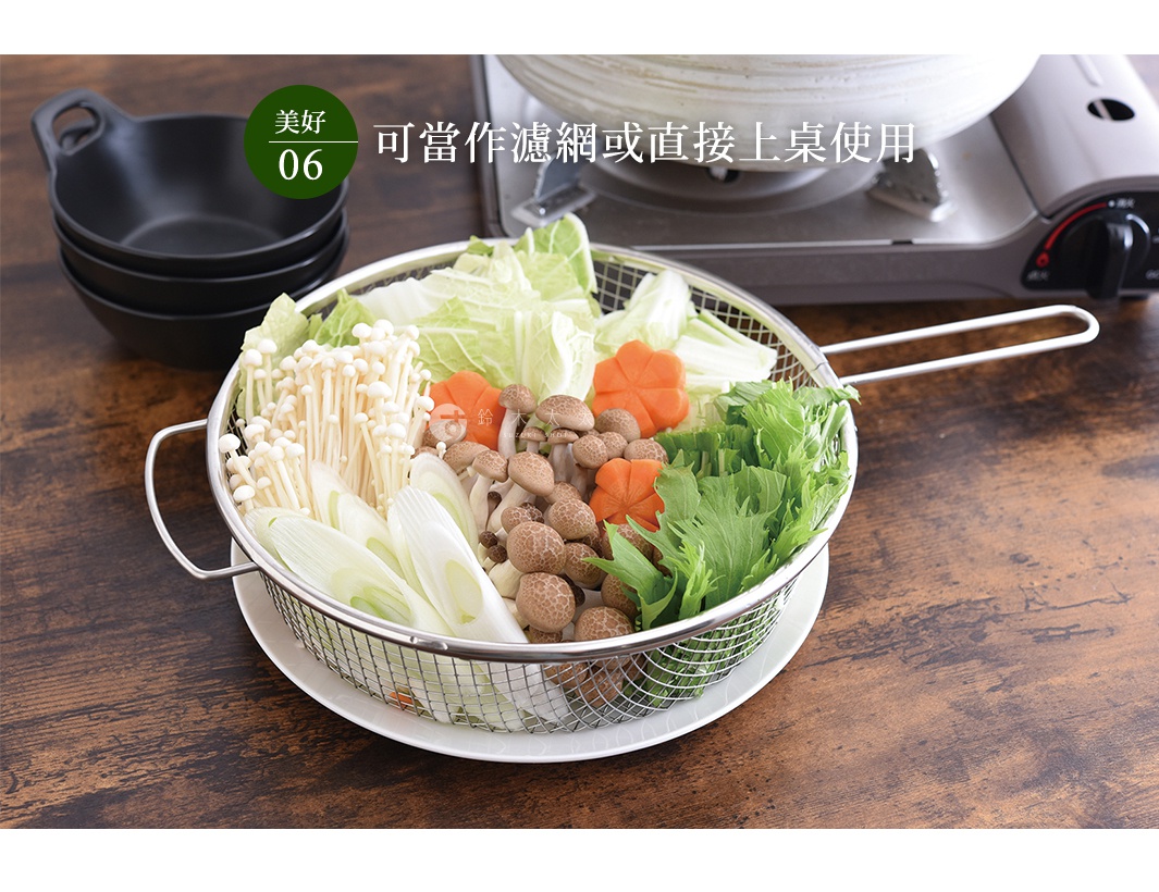 不鏽鋼手持料理濾網，裝有金針菇、鴻禧菇、大白菜、蔥段及綠葉蔬菜，濾網置於白色盤上，背景為木質桌面及卡式爐。