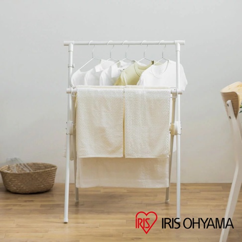 白色金屬X型曬衣架，上方掛有衣物，下方層架掛有兩條白色毛巾，整體簡約實用。