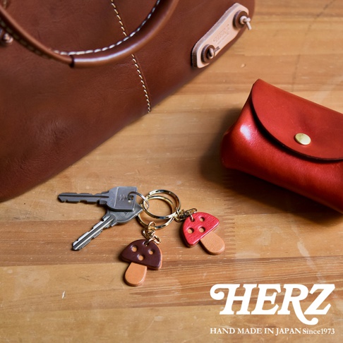 職人手作皮革香菇造型鑰匙圈，包含紅色和棕色香菇吊飾，搭配金屬鑰匙圈和兩把鑰匙。