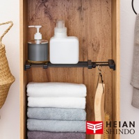 平安伸銅 HEIAN SHINDO 伸縮縫隙置物架，架上擺放著兩種洗劑瓶及疊好的毛巾，一旁掛著木柄刷。