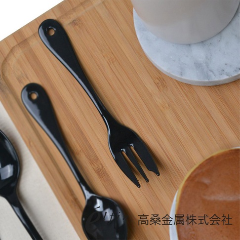 日製黑琺瑯水果甜點叉，特寫兩個黑色光滑琺瑯叉子，一個在上面，一個在下面，均有掛孔，放在木質托盤上。