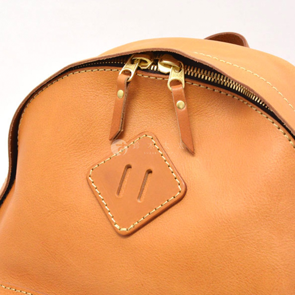 職人手作皮革休閒風後背包 R-93，特寫展示淺棕色皮革紋理，雙拉鍊設計，並有菱形皮革裝飾片。