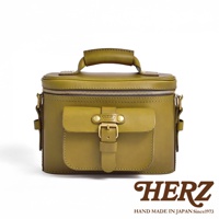 一手提皮革相機包，主體為橄欖綠色，有拉鍊封口，前方有一個帶金屬釦的翻蓋口袋，印有HERZ品牌標誌，背景為白色。