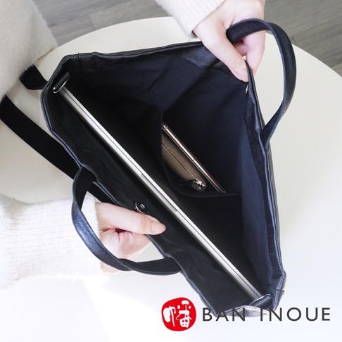 BAN INOUE 黑色釉面亞麻布三用托特包，內部可見一台筆記型電腦和一個卡夾，由一位女性手持。