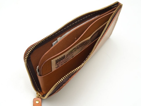 職人手作皮革L型拉鍊長夾，採用天然棕色皮革，質樸紋理，內有紙鈔與卡片，金色拉鍊環繞，設計簡約實用。