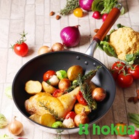 一個30公分輕量炒鍋，內含烤雞腿、馬鈴薯塊、小番茄、抱子甘藍、洋蔥和迷迭香，鍋柄為天然木材質，鍋身為銀色金屬。