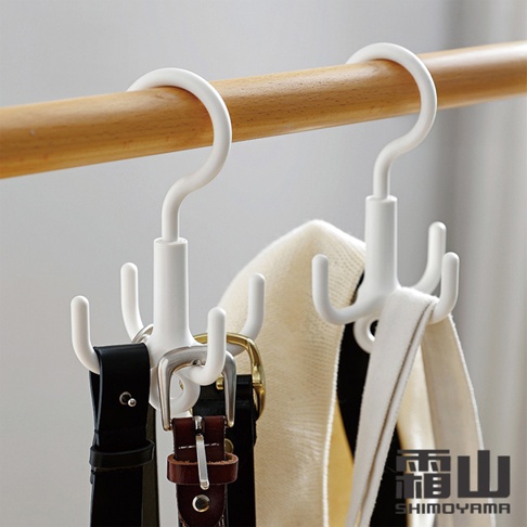 兩個白色ABS材質的四爪掛勾，掛在木質衣桿上，分別掛著皮帶和圍巾。