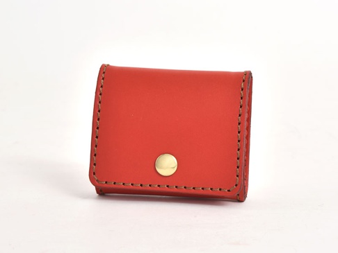 紅色皮革箱型零錢包，帶有金色按扣，採用手工縫製，邊緣有明顯的縫線。