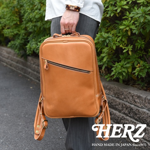 職人手作皮革長方型後背包，棕褐色，配有拉鍊主隔層和前置拉鍊口袋，質感皮革材質，簡約設計。