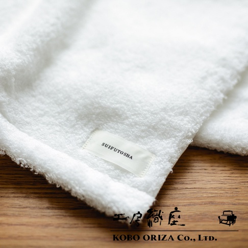 今治產白色匹馬棉毛巾，質地柔軟，表面有細緻的毛圈，一角縫有「SUIFUTOSHA」字樣的淺色布標。