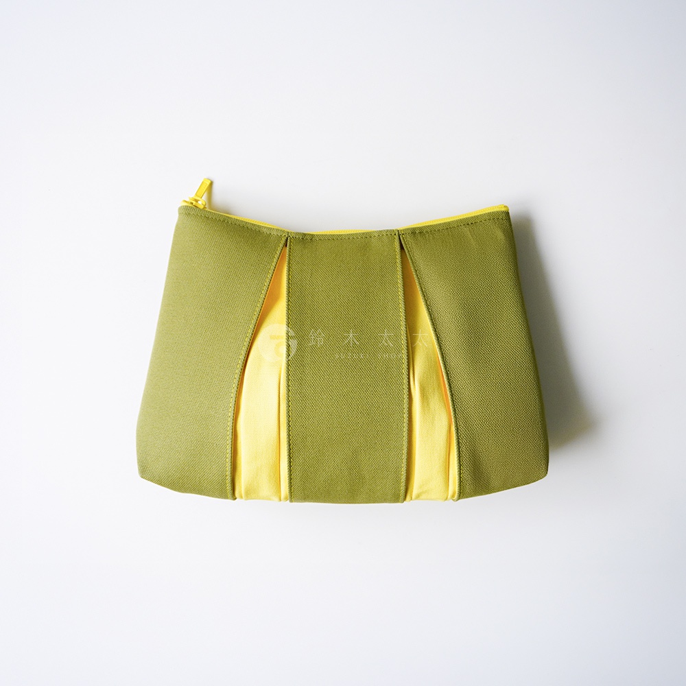 一個京都KOSHO品牌的ougi帆布化妝收納包，呈現橄欖綠色與亮黃色拼接設計，外觀具有立體的風琴摺皺細節，配有黃色拉鍊，整體為簡約時尚的帆布材質。