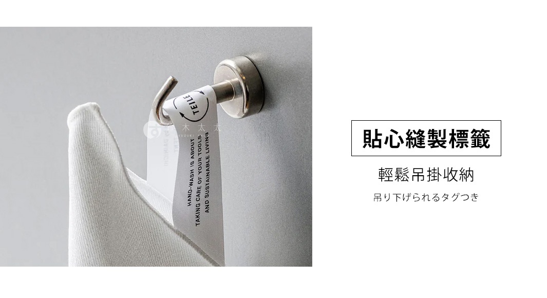 白色纖維擦拭巾，材質柔軟，帶有印有英文文字和圖案的吊掛標籤，透過金屬掛鉤懸掛在金屬表面。