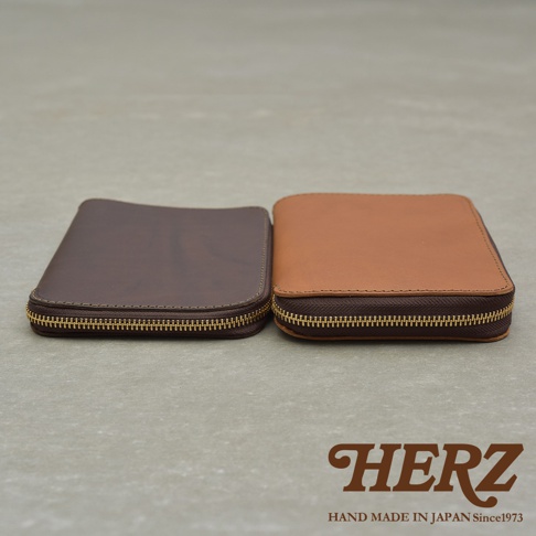 兩個職人手作皮革Organ記事本收納包，一個為深棕色，另一個為淺棕色，皆配有金色拉鍊。