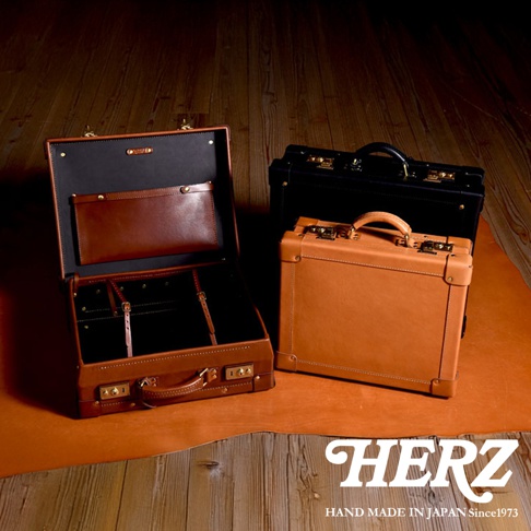 皮革手提行李箱，包含一個打開的棕色行李箱，內部有隔層和一個小皮袋，以及兩個關閉的行李箱，一個是棕色，另一個是黑色。