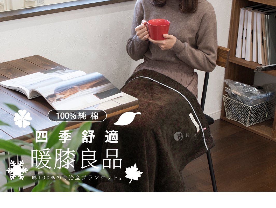 一位女子手捧紅色馬克杯，身蓋著暖色調的純棉膝蓋毯，毯子上印有「100%純棉」、「四季舒適」、「暖膝良品」等日文文字，旁邊還有四葉草、雪花和楓葉圖案。