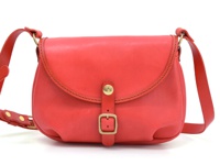 紅色皮革馬鞍包，帶有皮帶扣和金屬搭扣，適合休閒旅行。