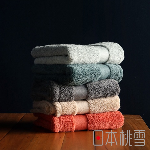 今治匹馬棉方巾堆疊展示，包含淺灰綠、藍綠、中灰、米白與珊瑚橘等五種顏色，材質為柔軟的匹馬棉。