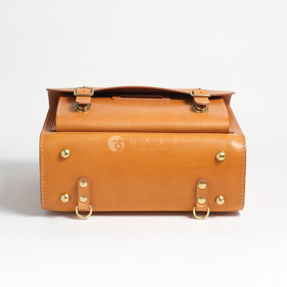職人手作皮革橫式書包，焦糖棕色，配有黃銅金屬扣環和铆釘，復古風格。