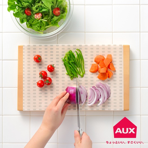 一張多功能砧板防汙紙，上面鋪有切好的紅蘿蔔塊、青椒絲、小番茄及切片的紅洋蔥。一張玻璃碗裝有綠色沙拉，上方點綴著小番茄切片。