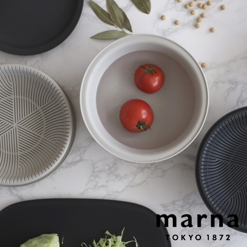 marna TOKYO 1872 品牌字樣，搭配兩個番茄泡在水中，旁邊有灰色的濾網和黑色的托盤，背景為大理石紋路。