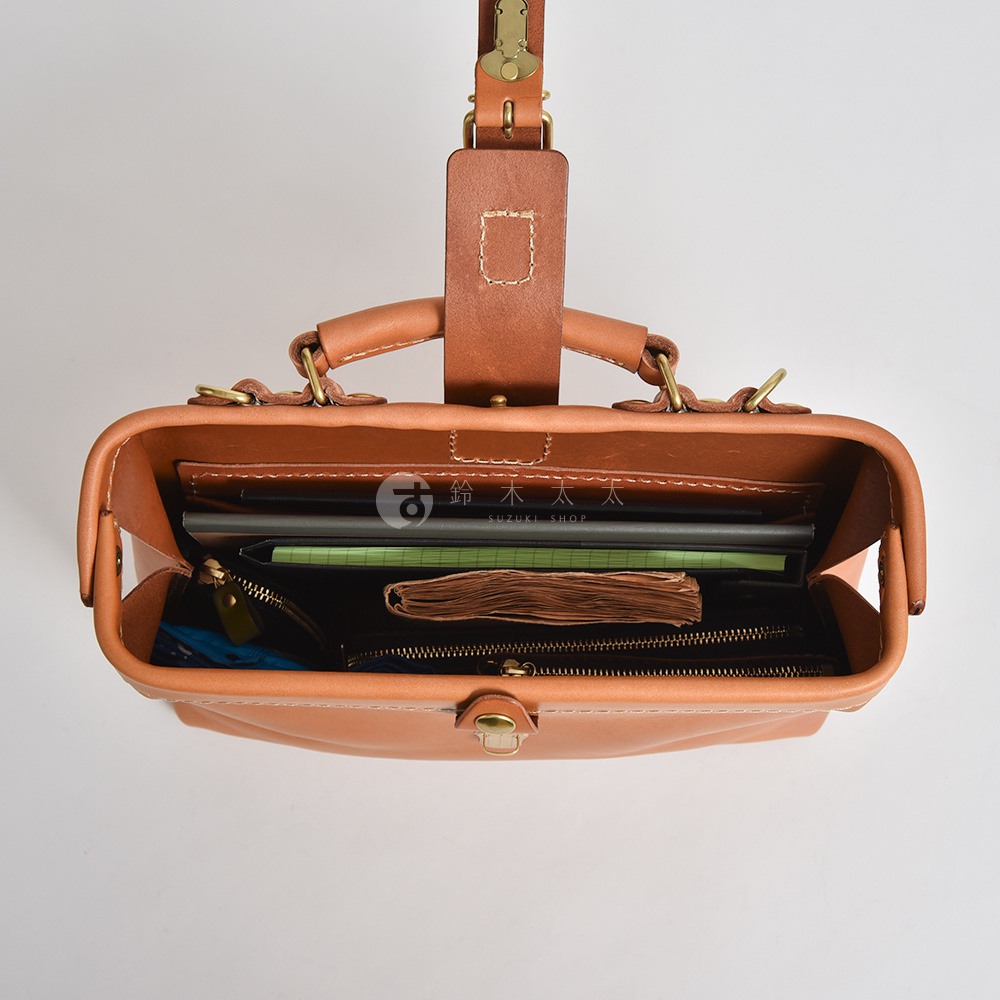 職人手作皮革迷你軟皮杜勒斯包，呈現自然棕色調，包身內部裝有筆記本、小冊子及拉鍊內袋。