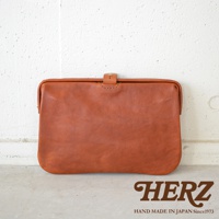 棕色皮革製成的職人手作Organ手拿包，採用簡約的設計，頂部有皮革搭扣和縫線細節，質感溫潤。