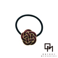 一款深紅色和金色線材編織而成的日式水引花結髮圈，搭配黑色彈性髮圈。