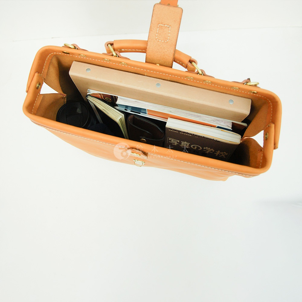 職人手作皮革軟式杜勒斯包，淺棕色，內部裝有書籍、筆記本、錢包和鏡頭蓋。