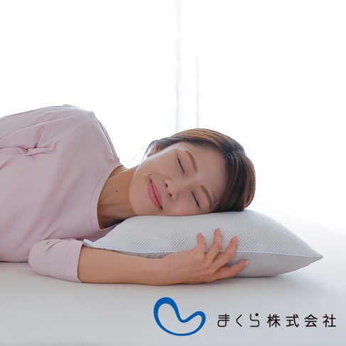 一位女士側臥，臉龐安詳地倚靠在一個淺灰色、網狀織物的低枕上。