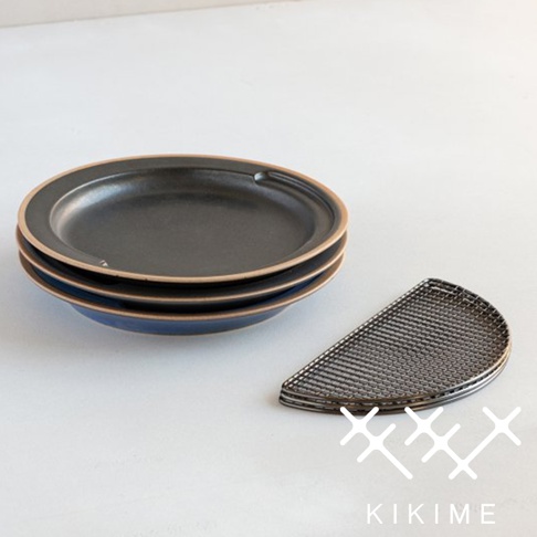 堆疊的深灰色美濃燒瀝油餐盤，盤緣帶有淺棕色，盤底為藍色。右側為一個金屬製半月形瀝油網架。