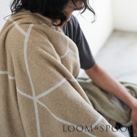 兩位人士坐著，其中一人披著一條淺棕色純棉浴巾，浴巾上印有白色幾何線條圖案。