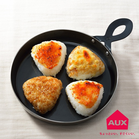 leye 披薩小鐵鍋內盛放著四個三角形的飯糰，其中兩個頂部覆蓋著融化的起司，另外兩個則淋有橙紅色的醬料。鍋身為黑色，帶有黑色弧形手柄。