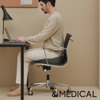 一名男性坐在辦公椅上，椅上有一個深綠色的低反發美姿支撐坐墊。