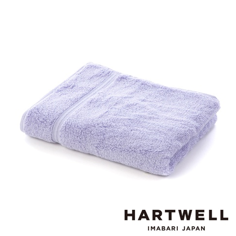 一條淺紫色、觸感柔軟的今治毛巾，折疊置於白色背景上，毛巾表面紋理清晰，邊緣有細緻的條紋裝飾。