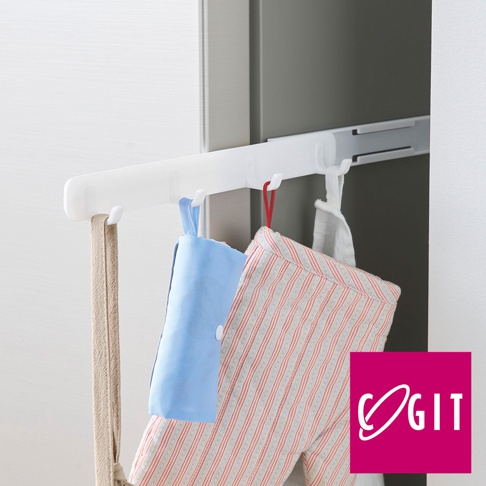 白色磁吸式縫隙專用四聯伸縮掛鉤，附有三個掛勾，懸掛著淺藍色摺疊袋、一條米色織帶和一條有紅色細條紋的布料。