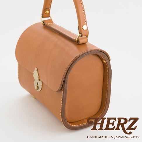 職人手作皮革復古杜勒斯手提包，採用棕褐色皮革製成，配有金色鎖扣和提把，縫線清晰，風格簡約。