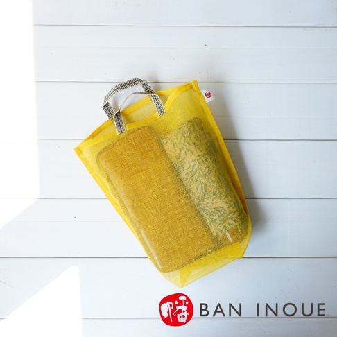 黃色網狀提把蔬果收納袋，袋內裝有兩卷物品，一卷為黃色素面，另一卷為綠色植物圖案。