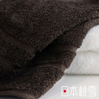 兩條蓬鬆柔軟的棉浴巾，一條為深棕色，另一條為白色，疊放在一起。