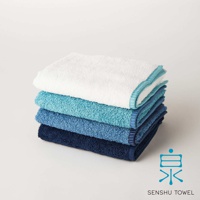 SOLID 細柔蓬韌緞澤長纖浴巾，堆疊展示四種不同深淺的藍色調，材質觸感蓬鬆，邊緣帶有織紋裝飾。