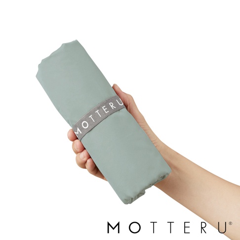 一隻手拿著摺疊起來的淺綠色大容量束口摺疊保冷可立托特袋，袋子上有一條灰色束帶，上面印有「MOTTERU」字樣。